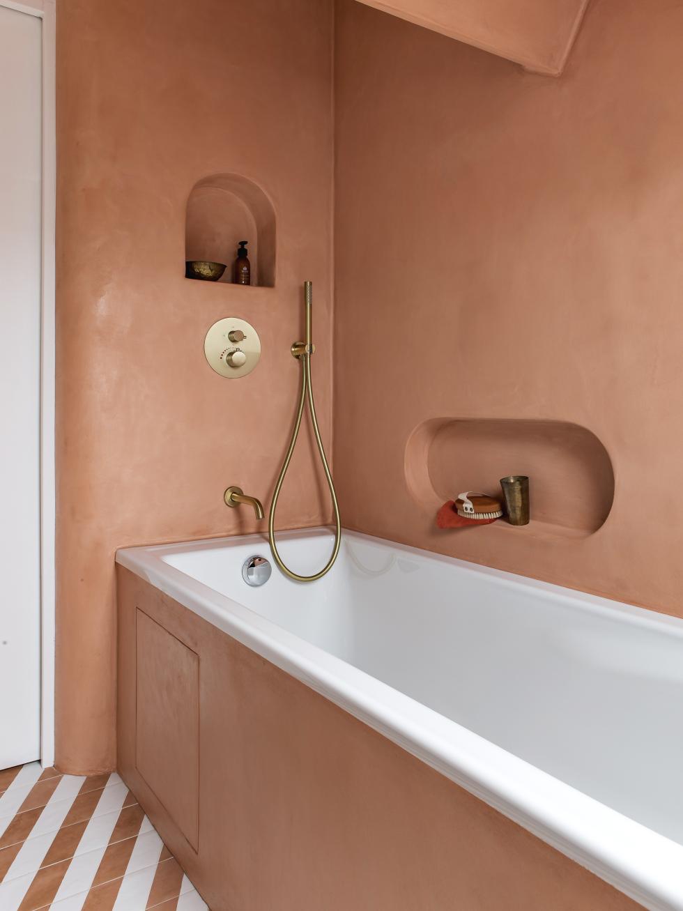 Badezimmer mit Badewanne, gewachsten Betonwänden und Messingarmaturen.