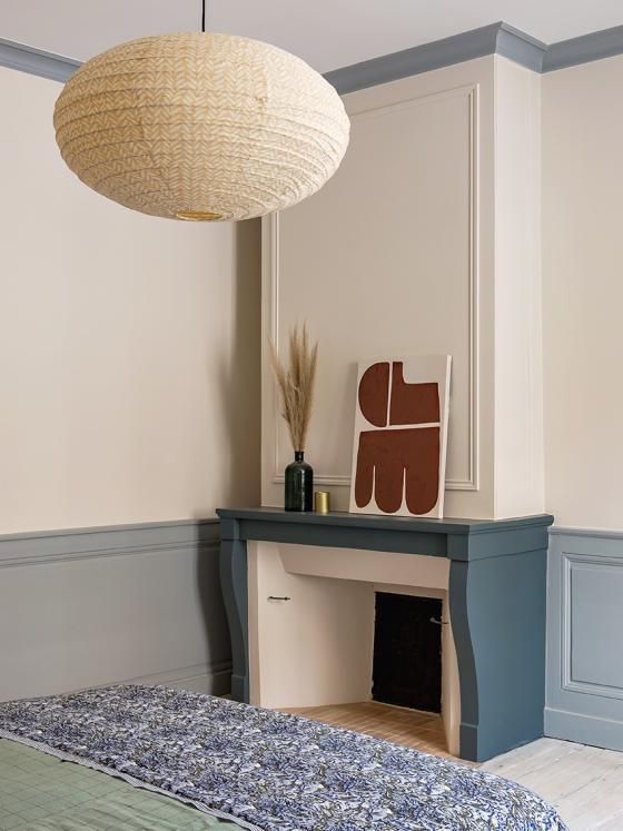 Elternschlafzimmer mit hellem Parkettboden und blau gestrichenem Kamin